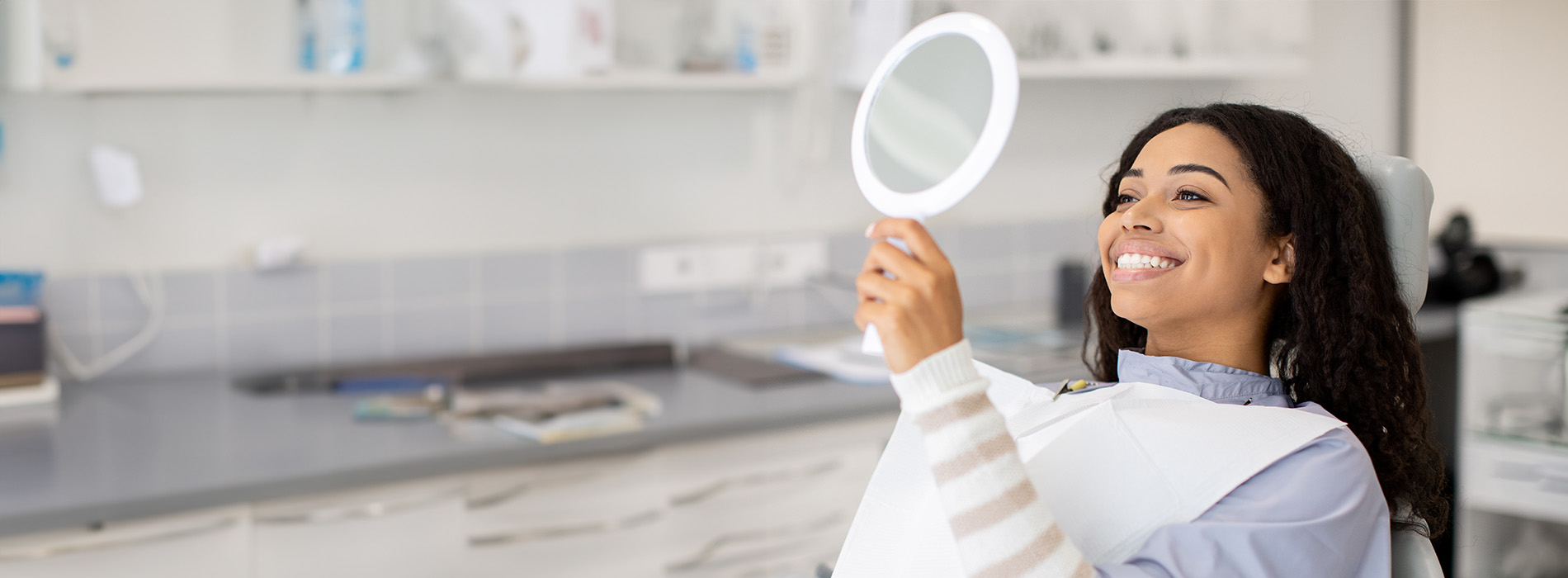 A woman with her back to the camera, holding a magnifying glass and examining something attentively in a laboratory setting.