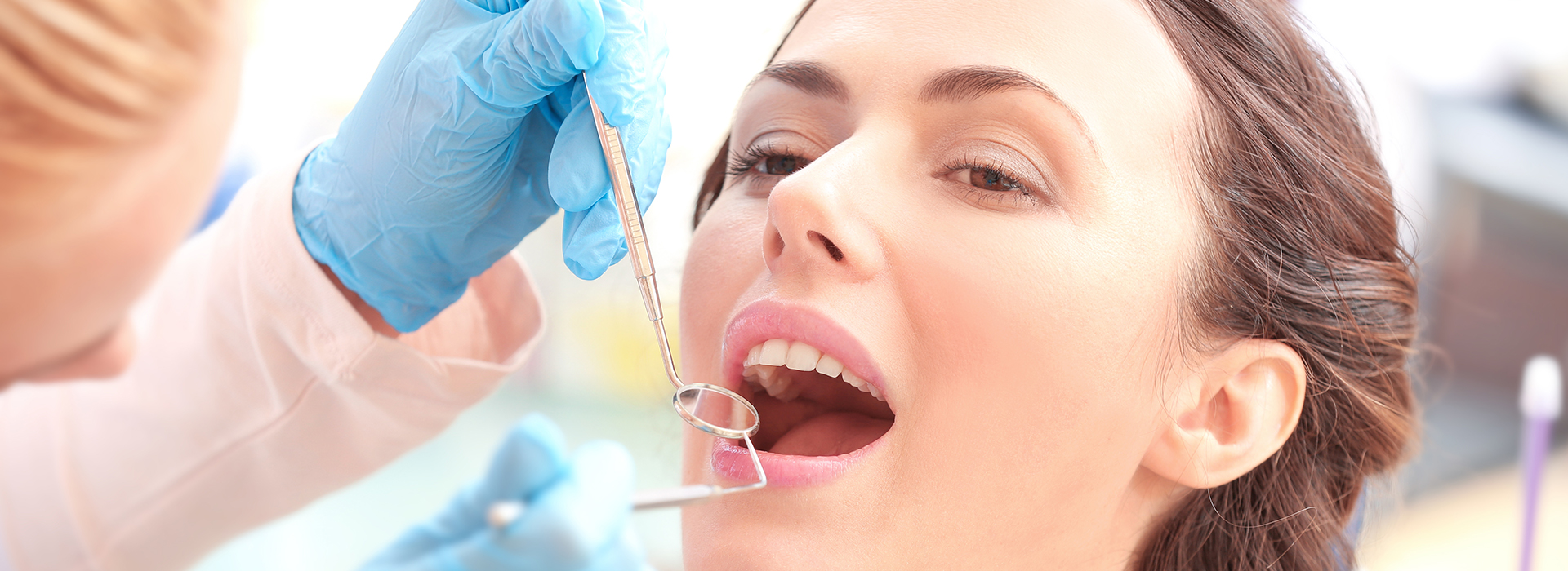 A woman receiving dental care with multiple people assisting her, focusing on her mouth and teeth.