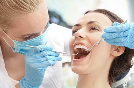 A dental hygienist performing oral care on a patient s teeth with a drill.